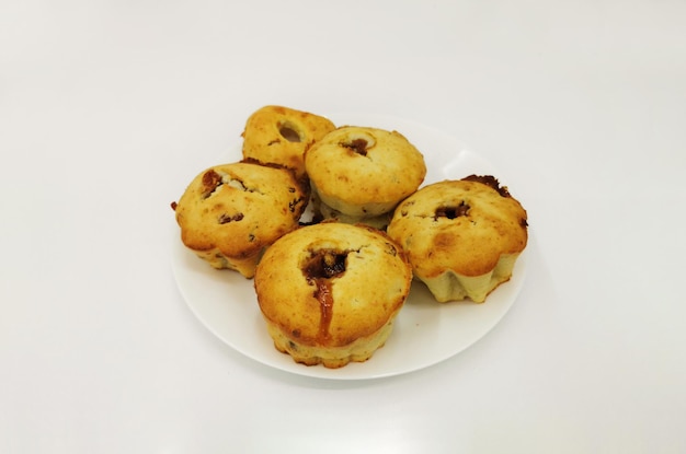 Delicious homemade muffins with raisins prunes and jam inside on a white plate Home baking