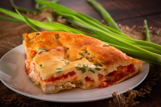 Delicious homemade pie with chicken, herbs and tomatoes on a plate.