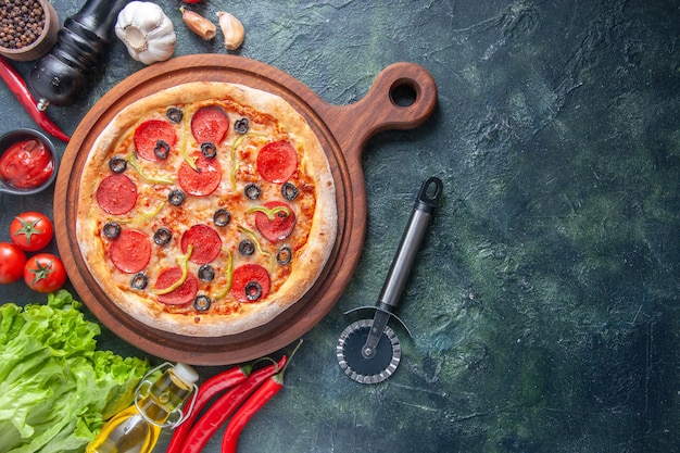 Deliziosa pizza fatta in casa su tagliere di legno pomodori aglio ketchup fascio verde bottiglia di olio pepe su superficie scura