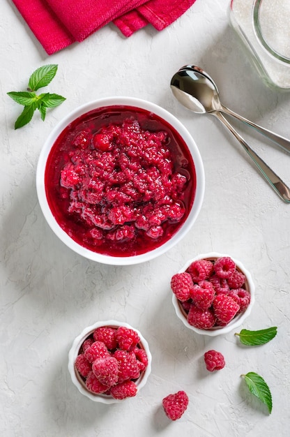 Delicious homemade raspberry jam in a bowl on a light table Top view