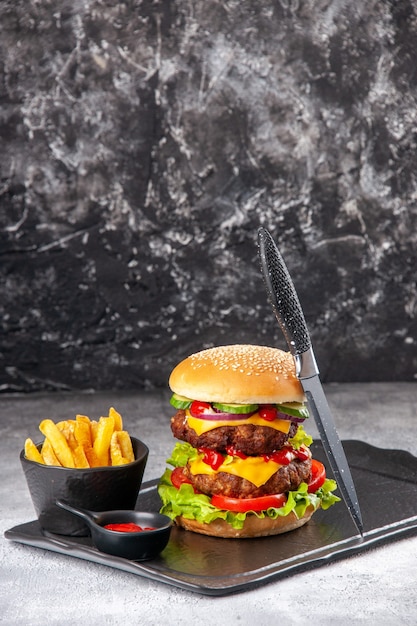 Delicious homemade sandwich and fork ketchup fries green on black board on gray isolated surface