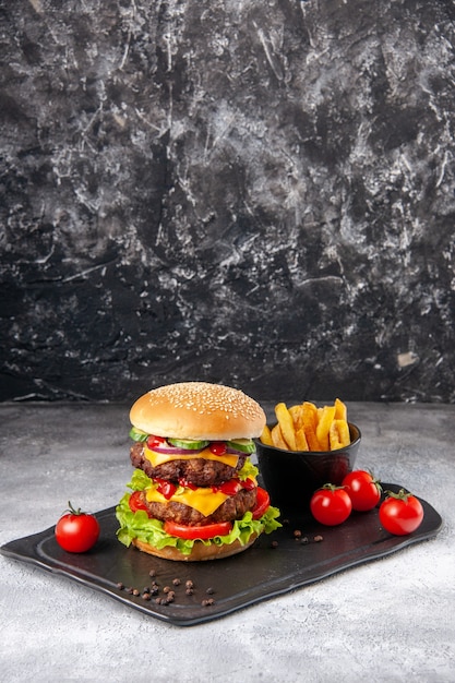 Delicious homemade sandwich and fries ketchup on black board on gray ice surface with free space