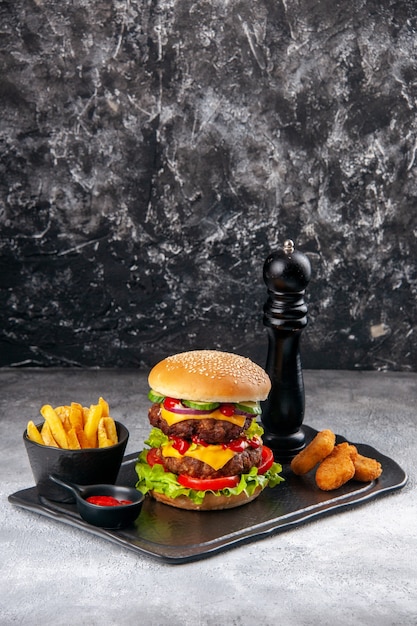 Delicious homemade sandwich and ketchup fries chicken nuggets\
on black board on gray distressed surface