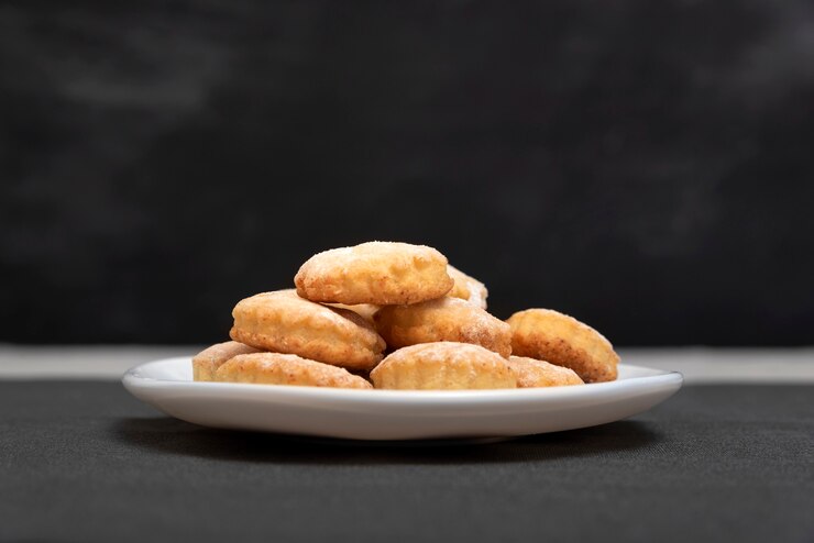 Delicious homemade shortcake on white plate, black surface. Side view. Fresh shortbread.
