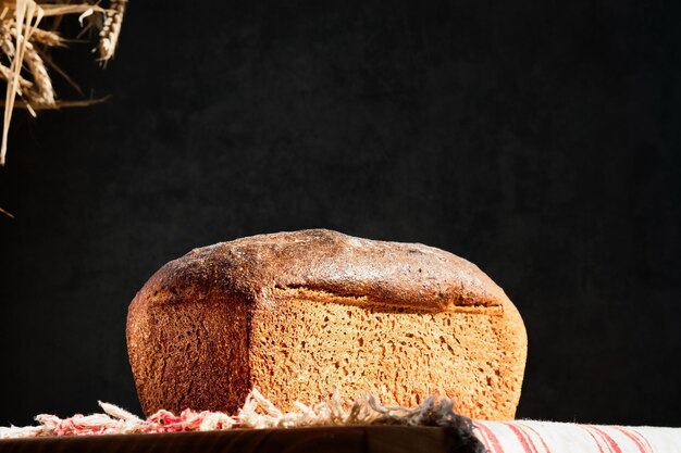 Delicious homemade sourdough baked bread Freshly baked artisan whole grain bread from rye and wheat sourdough on rustic gray kitchen towel dark background Selective focus on a loaf of bread