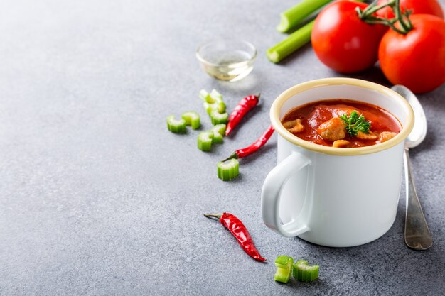 Delicious homemade tomato soup with meatballs in enamel mug. 