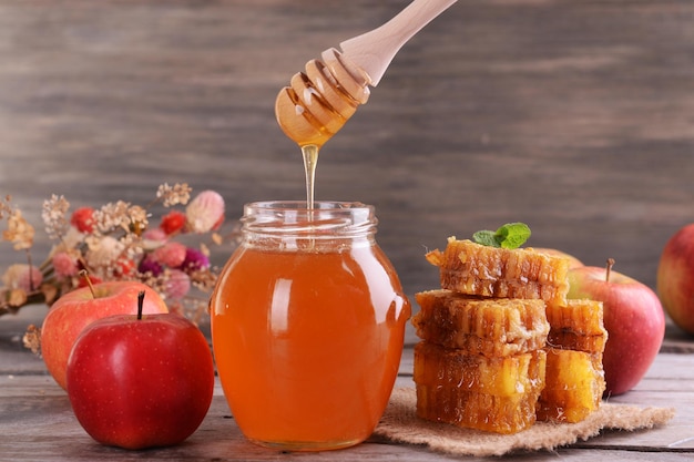 Delicious honey with apple on table on wooden background