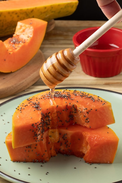 Delicious honey with papaya on plate Selective focus