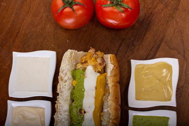 Foto delizioso hot dog con ingredienti e su sfondo colorato o in legno