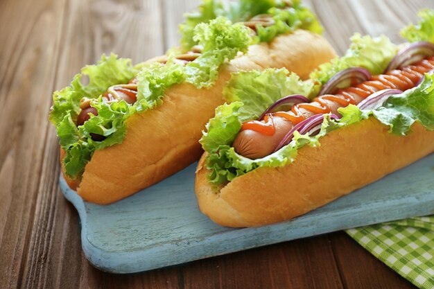 Delicious hot dogs on wooden board