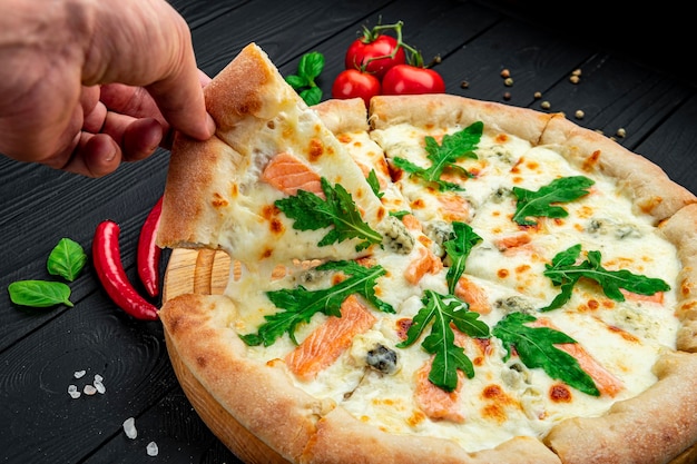 Delicious hot pizza with salmon arugula and different spices on wooden table ready to eat