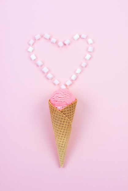 Delicious ice cream in a waffle cone with a marshmallow heart on a pink background