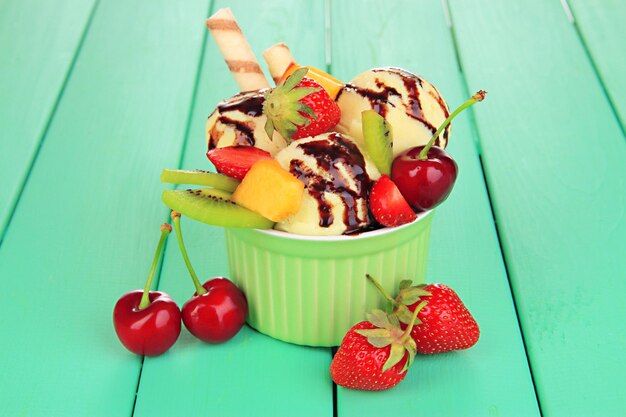 Delicious ice cream with fruits and berries in bowl on wooden table