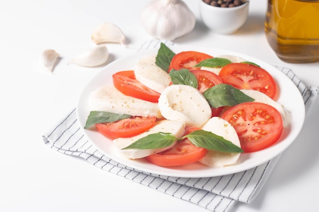 Delicious Italian caprese salad with sliced mozzarella tomatoes basil pesto and garlic on background