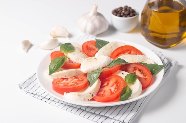 Delicious Italian caprese salad with sliced mozzarella tomatoes basil pesto and garlic on background