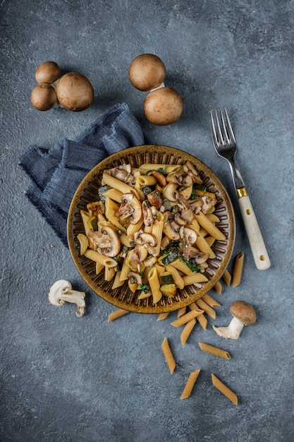 사진 맛있는 이탈리아 요리, 스패 나치, 호박, 푸른 대리석 질감 테이블에 마늘과 구운 버섯 펜네 파스타. 일체형 파스타와 전체 샴 피뇽 버섯