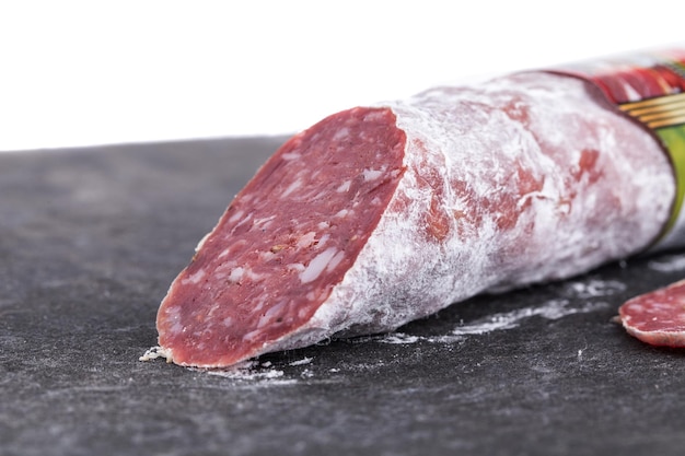 Photo delicious italian felino salami stick macro salami located on black cardboard and isolated against white background