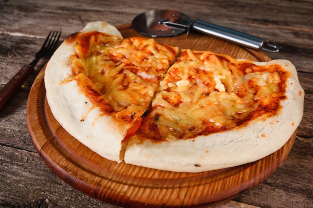 Delicious italian folded stuffed pizza calzone with baked cheese, served on rustic wooden table, close up.