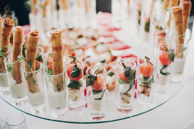 Photo delicious italian food table at wedding reception tomatoes basilcheeseprosciutto greenery and bread appetizers on table at wedding or christmas feast luxury catering concept