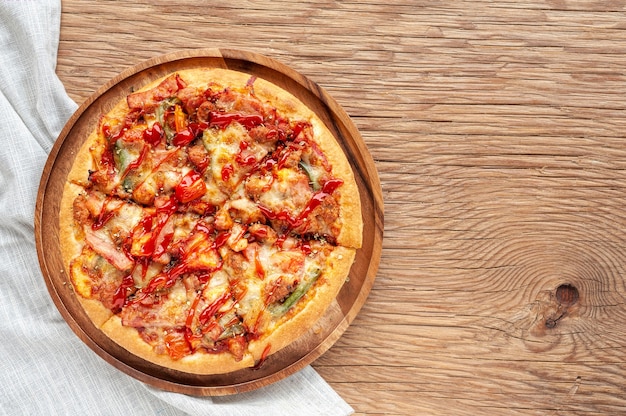 おいしいイタリアのピザは、ベーコン、チーズ、トマト、トマト、木製のプレート上にスライスしました。