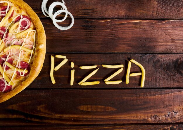 delicious Italian pizza with French fries on a wooden table