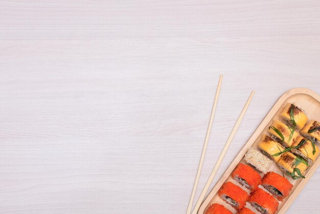 Delicious Japanese rolls with salmon avocado cucumber cheese on wooden plate with wood sticks with selective focus Asian food concept Healthy eating