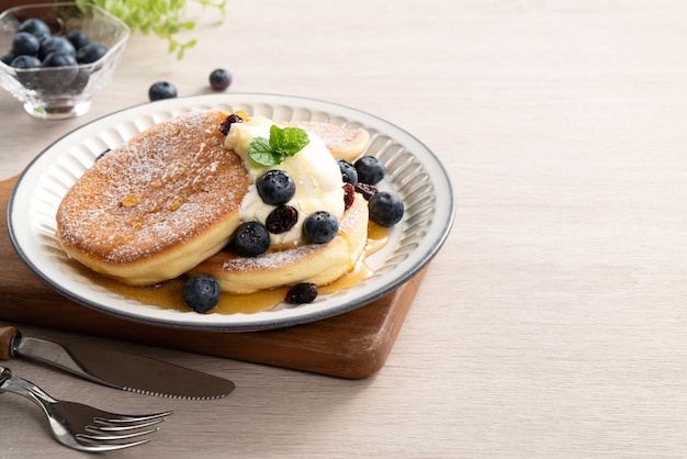 Delicious japanese souffle pancake with blueberry cranberry and\
honey on wooden table background