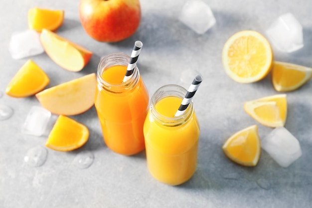 Delicious juices in bottles and fruits on table