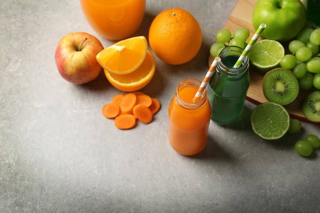 Delicious juices in bottles and fruits on table