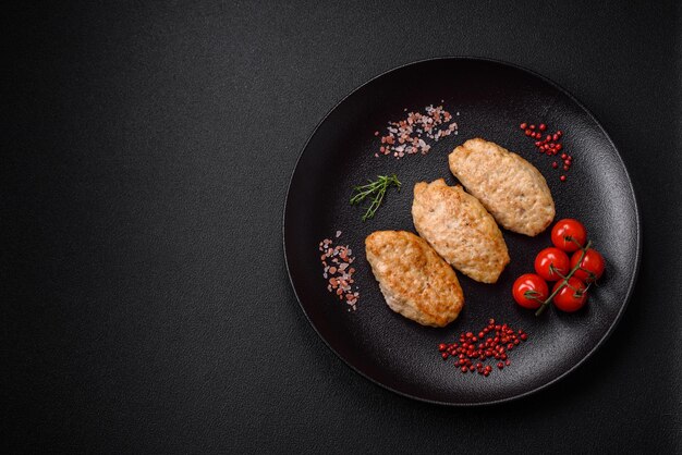 Delicious juicy cutlets or meatballs from minced chicken with salt and spices on a textured concrete background