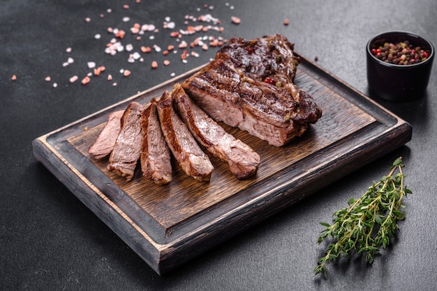 Delicious juicy fresh beef steak with spices and herbs on a dark concrete background. Grilled dishes