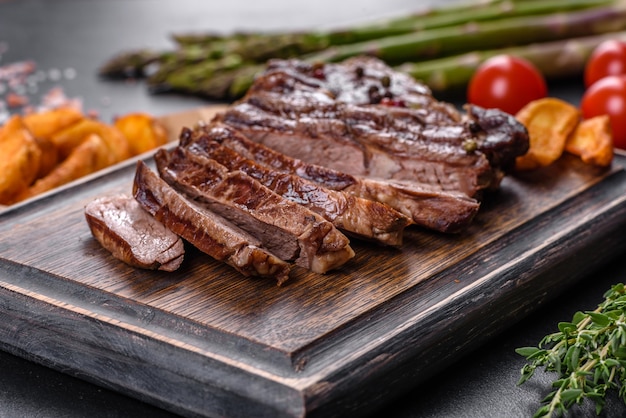 Delicious juicy fresh beef steak with spices and herbs on a dark concrete background. Grilled dishes