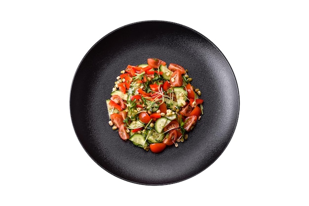 Photo delicious juicy fresh salad of tomatoes peppers cucumber microgreens and sprouted mung bean on a black ceramic plate on a dark concrete background