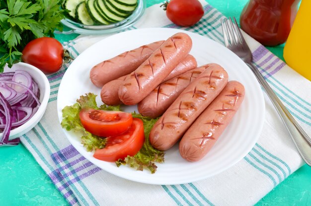 접시, 야채, 케첩과 겨자 밝은 배경에 맛있는 육즙이 구운 된 소시지.