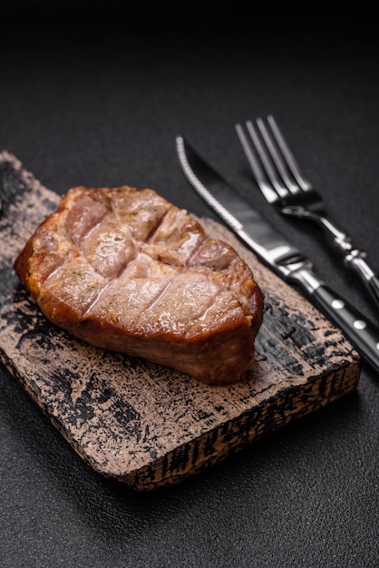 Foto deliziosa bistecca di maiale o manzo cotta alla griglia con sale e spezie su uno sfondo di cemento strutturato