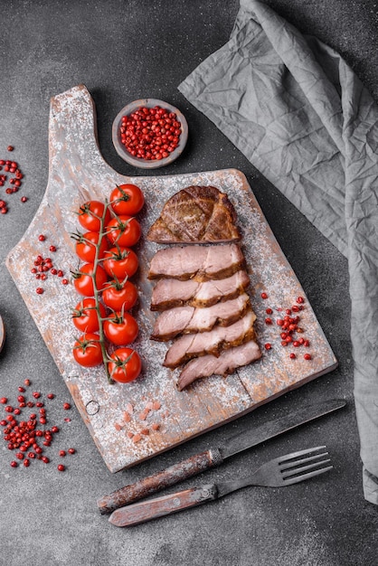 Delicious juicy pork or beef steak grilled with salt spices and herbs on a textured concrete background