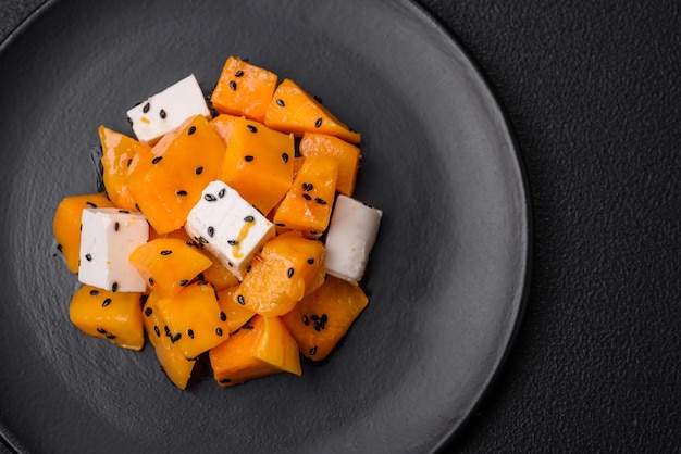 Delicious juicy salad of diced grilled pumpkin with feta cheese spices and sesame seeds on a ceramic plate
