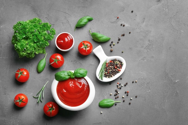 Photo delicious ketchup in bowl with ingredients on dark background top view
