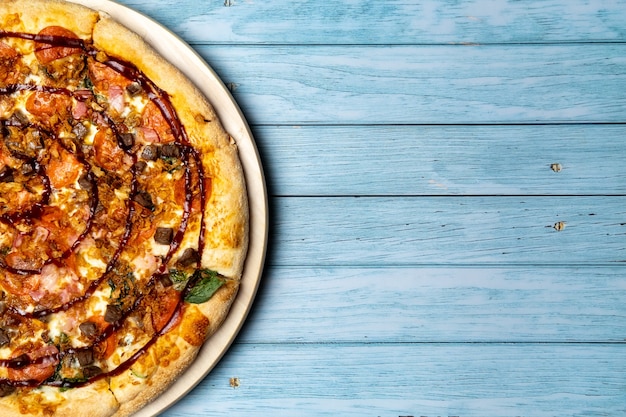 Delicious large pizza with bacon and spinach on a blue wooden background