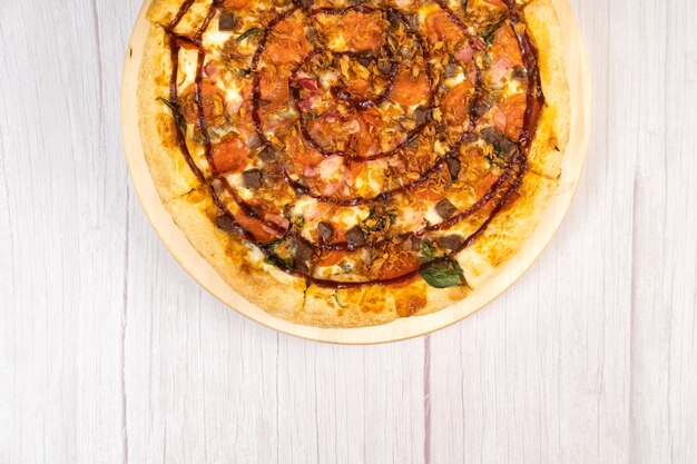 Delicious large pizza with bacon and spinach on a light wooden background