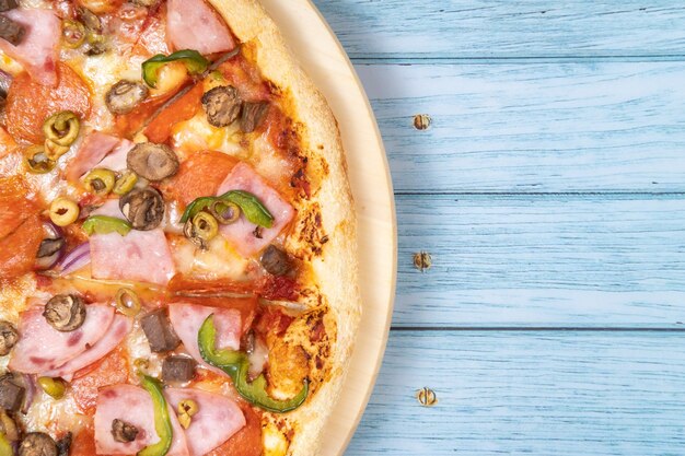 Delicious large pizza with veal and mushrooms on a blue wooden background.