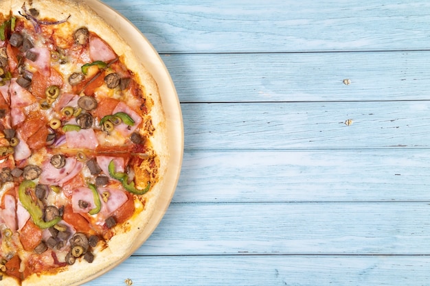 Delicious large pizza with veal and mushrooms on a blue wooden background.