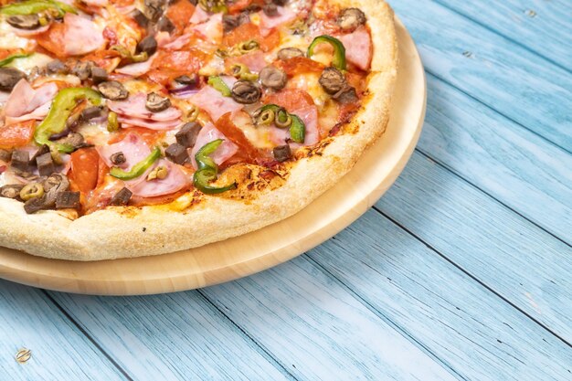 Delicious large pizza with veal and mushrooms on a blue wooden background.