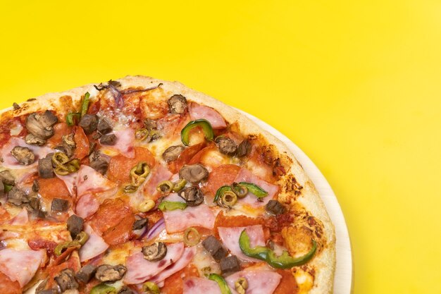 Вкусная большая пицца с телятиной и грибами на желтом фоне.