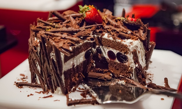 Delicious layered chocolate cake decorated with grated chocolate and strawberry fruit