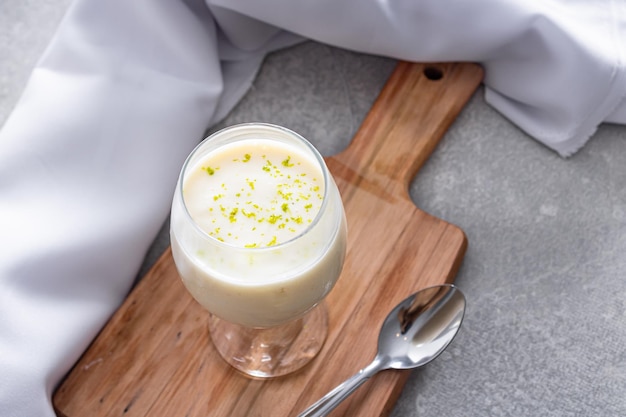 Delicious lemon mousse on a wooden board and a white table background with a white tablecloth around it and a metal spoon