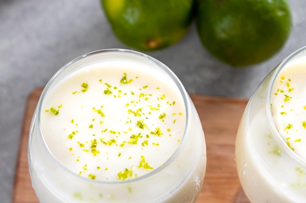 Photo delicious lemon mousse on a wooden board and a white table background with whole and sliced lemons in the background and a metal spoon