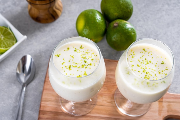 Delicious lemon mousse on a wooden board and a white table background with whole and sliced lemons in the background and a metal spoon