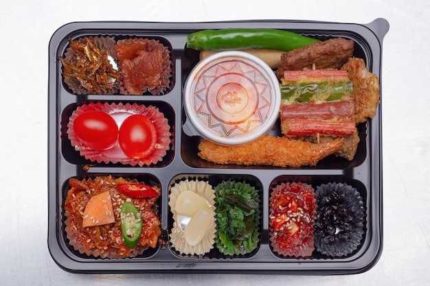 A delicious-looking lunch box with a variety of side dishes, fruits and tempura