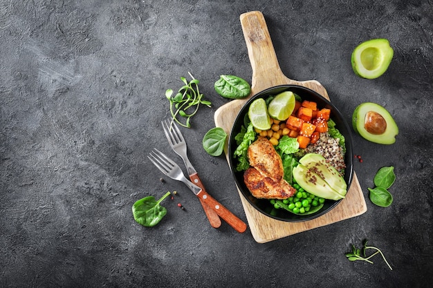 Photo delicious lunch with quinoa, avocado, sweat potato, fried chicken and seasoning on dark background. top view.